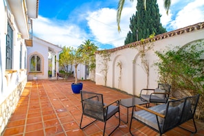 A courtyard with a tiled floor, a table with chairs, and a large planter. - Luxury Villa With Jacuzzi and sea Views (Nerja)