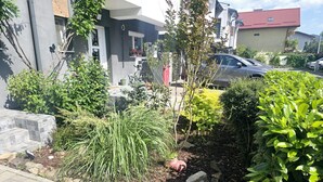 Un giardino residenziale con diverse piante e un vialetto lastricato.