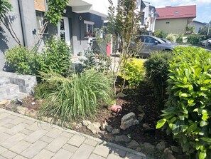 A residential garden with various plants and a paved walkway. - A cosy villa with private garden and free parking, on the outskirts of Bucharest (Bragadiru)