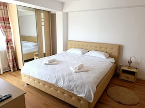A hotel room with a large bed, a bedside table with a lamp, and a mirror.