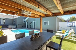 An outdoor pool area with a table and chairs, a hot tub, and a basketball hoop. - 4-bedroom house with pool and hot tub.  Walking distance to downtown Spearfish. (Spearfish)