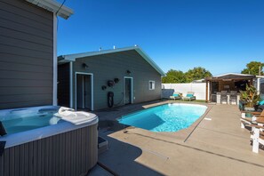 Ein Garten mit Schwimmbad, Whirlpool und Sitzgelegenheit im Freien.