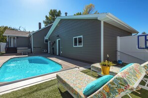 A backyard with a swimming pool, a covered hot tub, and a patio area with lounge chairs and a small table. - 4-bedroom house with pool and hot tub.  Walking distance to downtown Spearfish. (Spearfish)