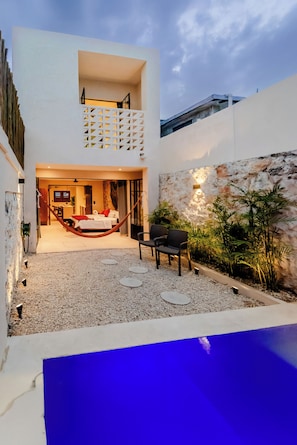 Ein moderner Außenbereich mit Pool, Sitzgelegenheit und Blick zum Himmel.