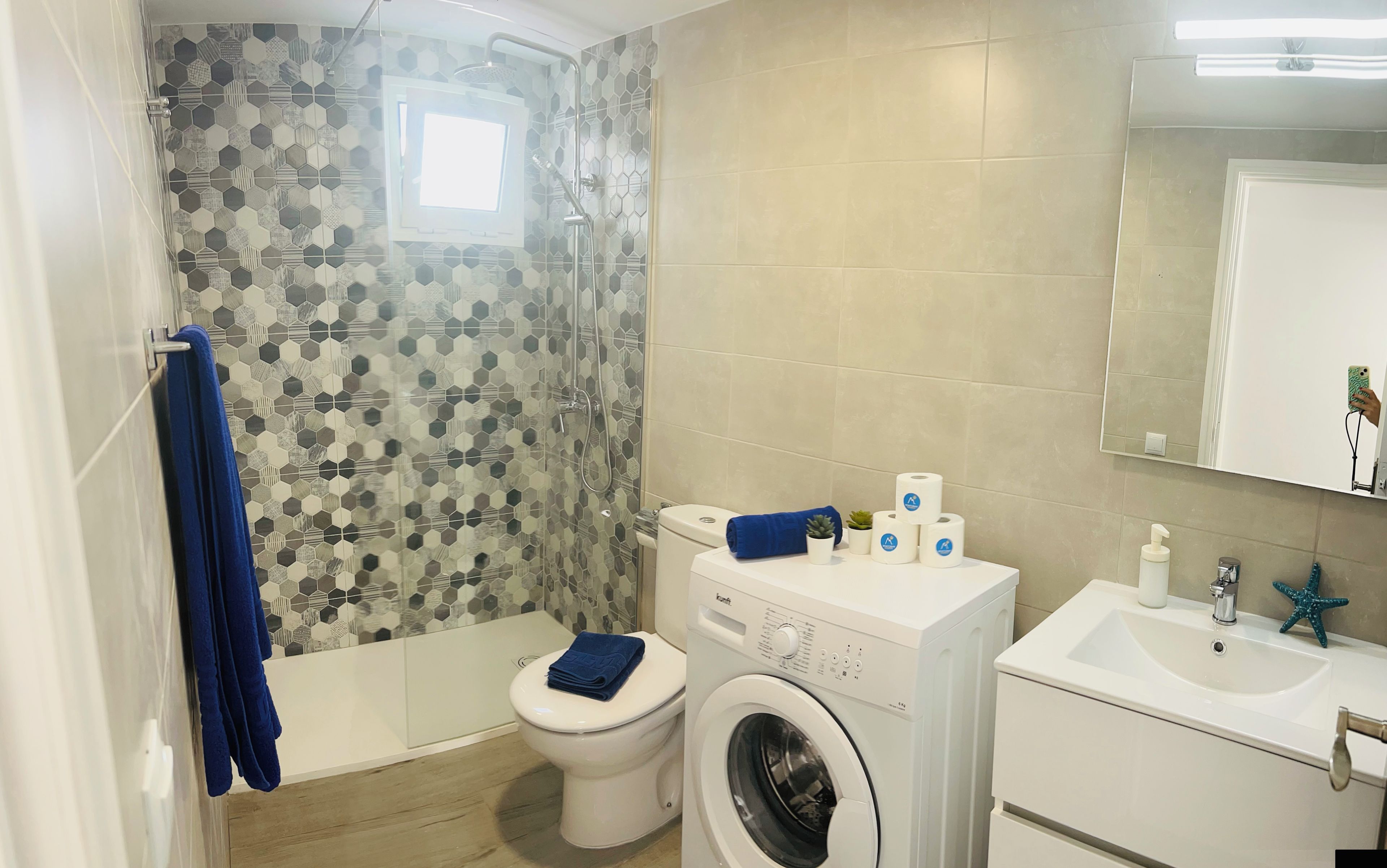 Un baño con ducha, inodoro, lavadora y lavamanos.
