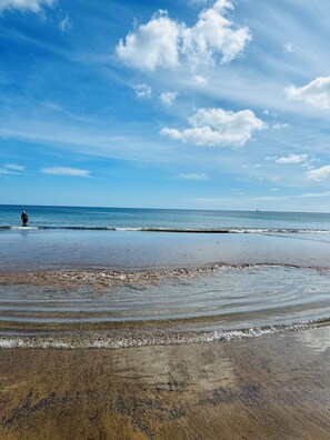 Ein Strand mit klarem Himmel und sanften Wellen.
