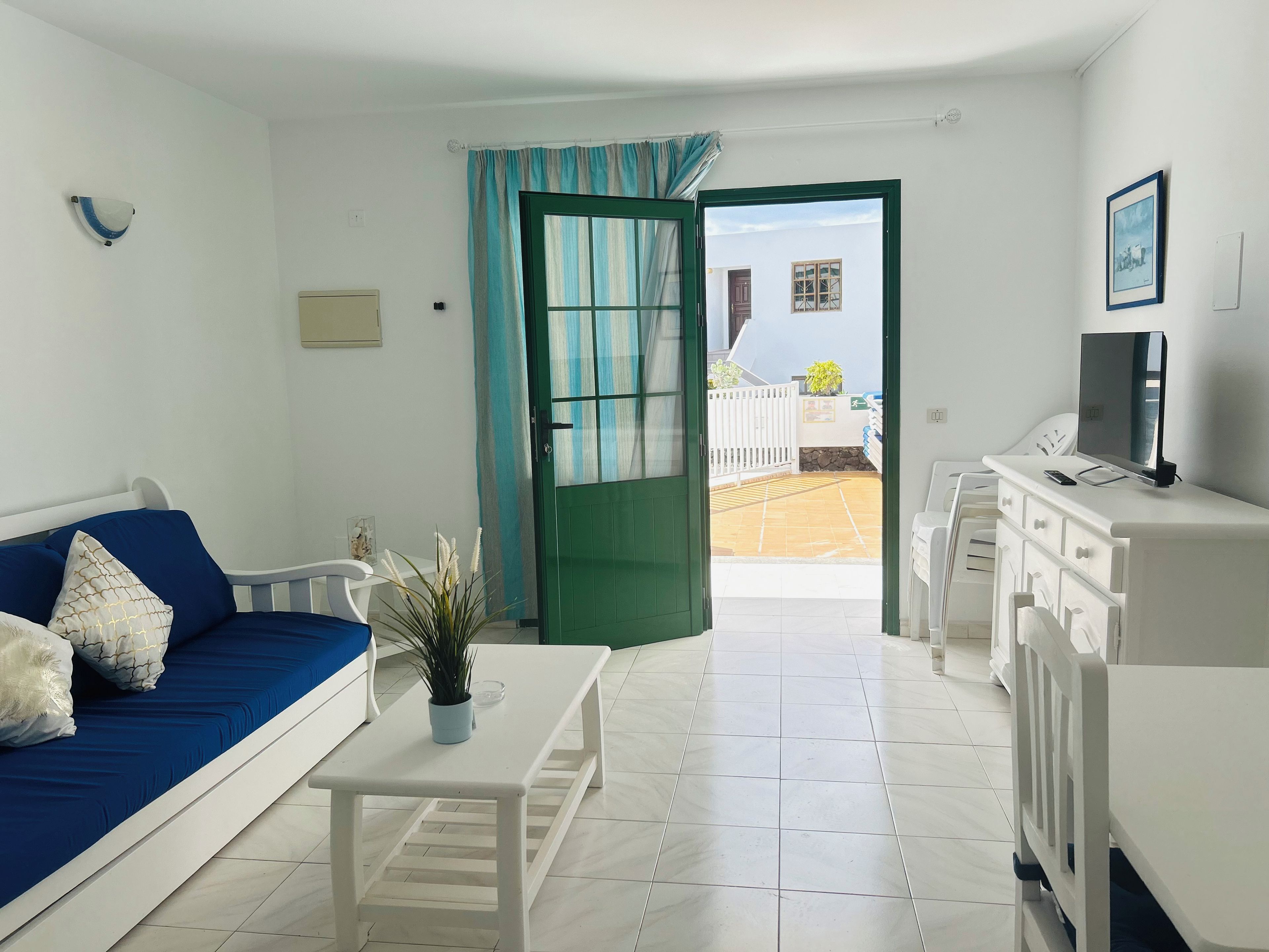 Una sala de estar moderna con un sofá, una mesa de centro, un televisor y vista a un patio.