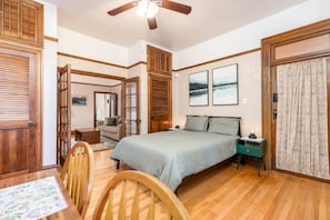 Ein Schlafzimmer mit einem Bett, Holzmöbeln, einem Deckenventilator und Kunstwerken an den Wänden.