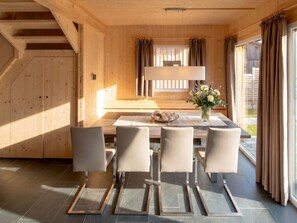 Ein Holzinterieur mit einem Esstisch, Stühlen und einer Blumenvase.