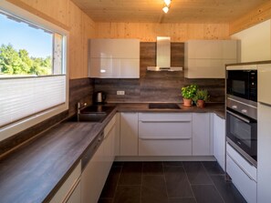 A modern kitchen with a built-in stove, oven, and sink. - One-bedroom Cabin (Sankt Georgen am Kreischberg)