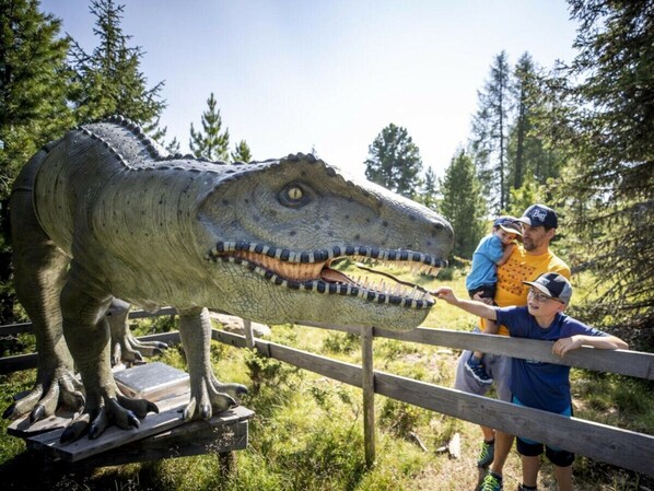 A large dinosaur sculpture with a wooden fence in the foreground. - One-bedroom Cabin (Sankt Georgen am Kreischberg)