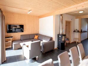 Una sala de estar moderna con un sofá seccional, un televisor de pantalla plana, una chimenea y un comedor con sillas.