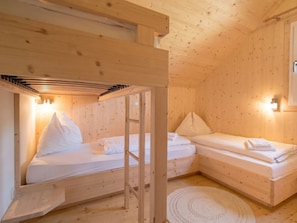 A wooden cabin with bunk beds, a woven rug, and wall-mounted lights. - One-bedroom Cabin (Sankt Georgen am Kreischberg)