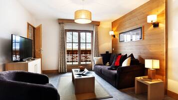 Ein modernes Wohnzimmer mit Fernseher, Sofa, Couchtisch und Holzelementen.