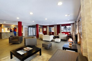 Un hall d’hôtel comprenant un comptoir d’accueil, un espace salon et une vue sur l’extérieur.