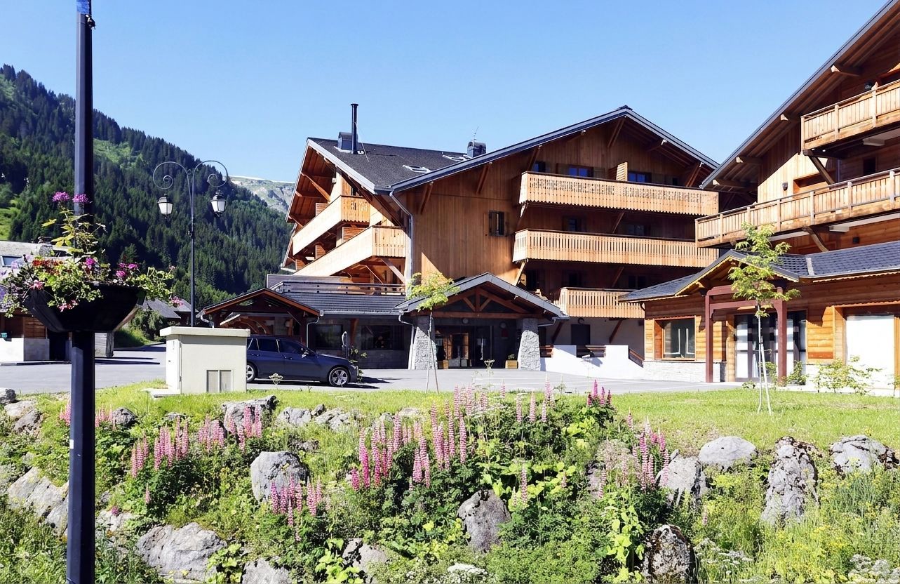 Un bâtiment en bois doté de nombreux balcons, d’une façade en pierre et offrant une vue dégagée sur le paysage environnant.