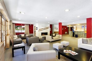 Un hall d’hôtel doté de plusieurs espaces aménagés avec des sièges, d’un comptoir de réception et d’une cheminée.