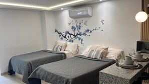 Ein Hotelzimmer mit zwei Betten, einer Wand-Klimaanlage und einem Essbereich mit Tellern und Gläsern.