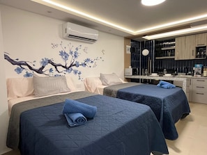 Ein Hotelzimmer mit zwei Betten, einer Küchenzeile und einem Wandgemälde.