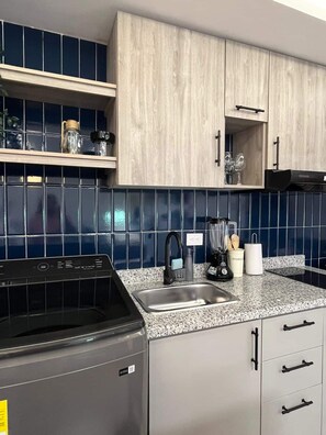 Eine Küche mit Granit Arbeitsplatte, Edelstahlspüle und Holzschränken.