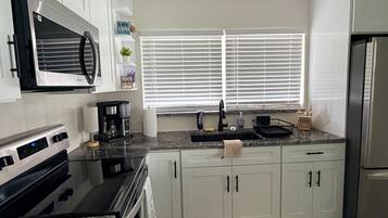 Een moderne keuken met witte kastjes, een roestvrijstalen koelkast en een inbouwoven.