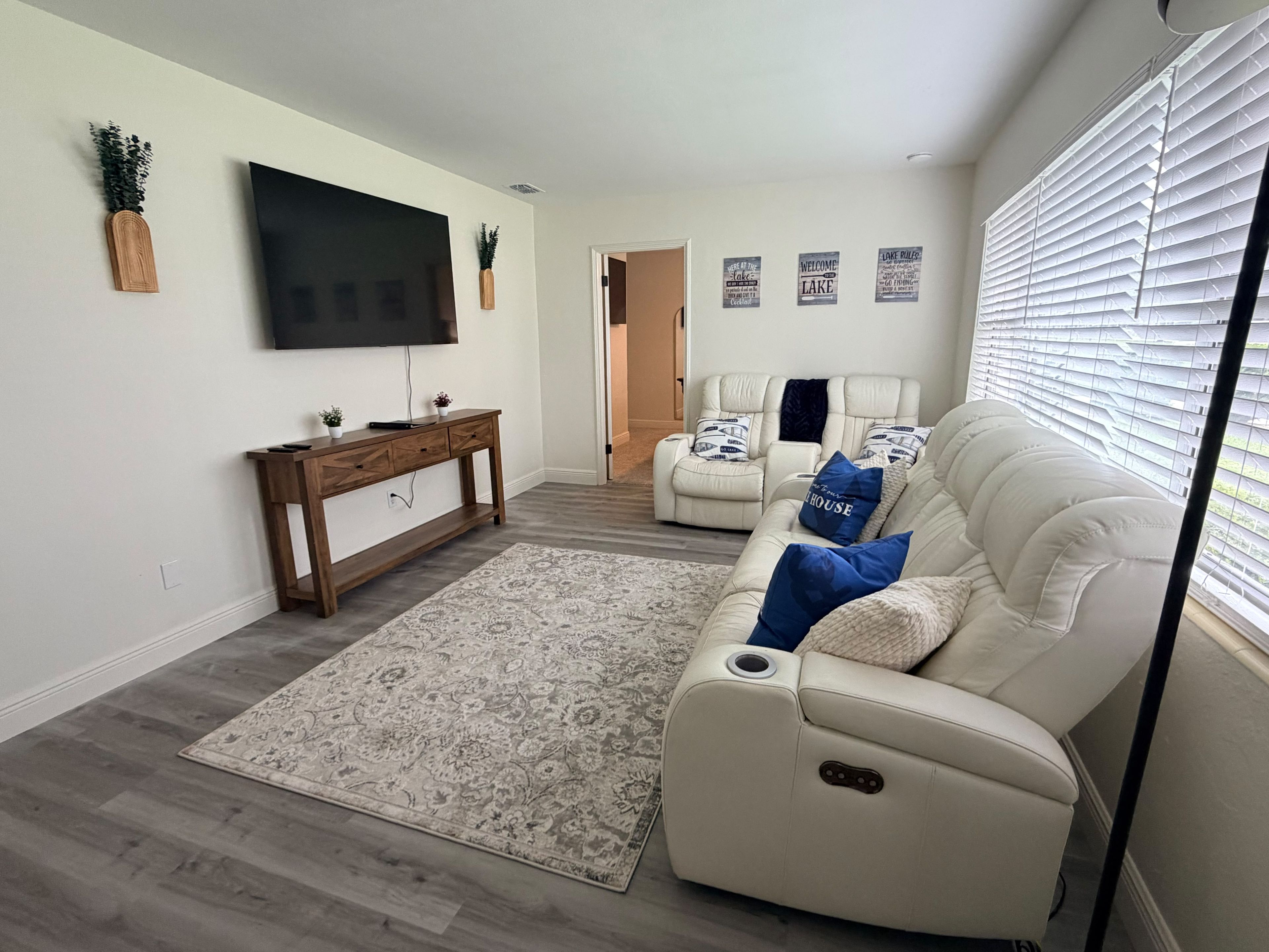 A living room with a sofa, a flat-screen TV, a wooden console, and a patterned rug.