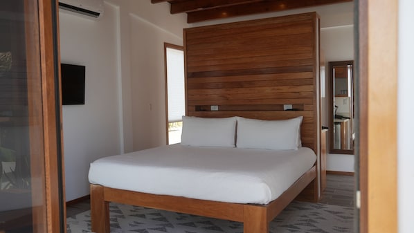 A bedroom with a wooden headboard, a bed with white bedding, and a patterned rug.