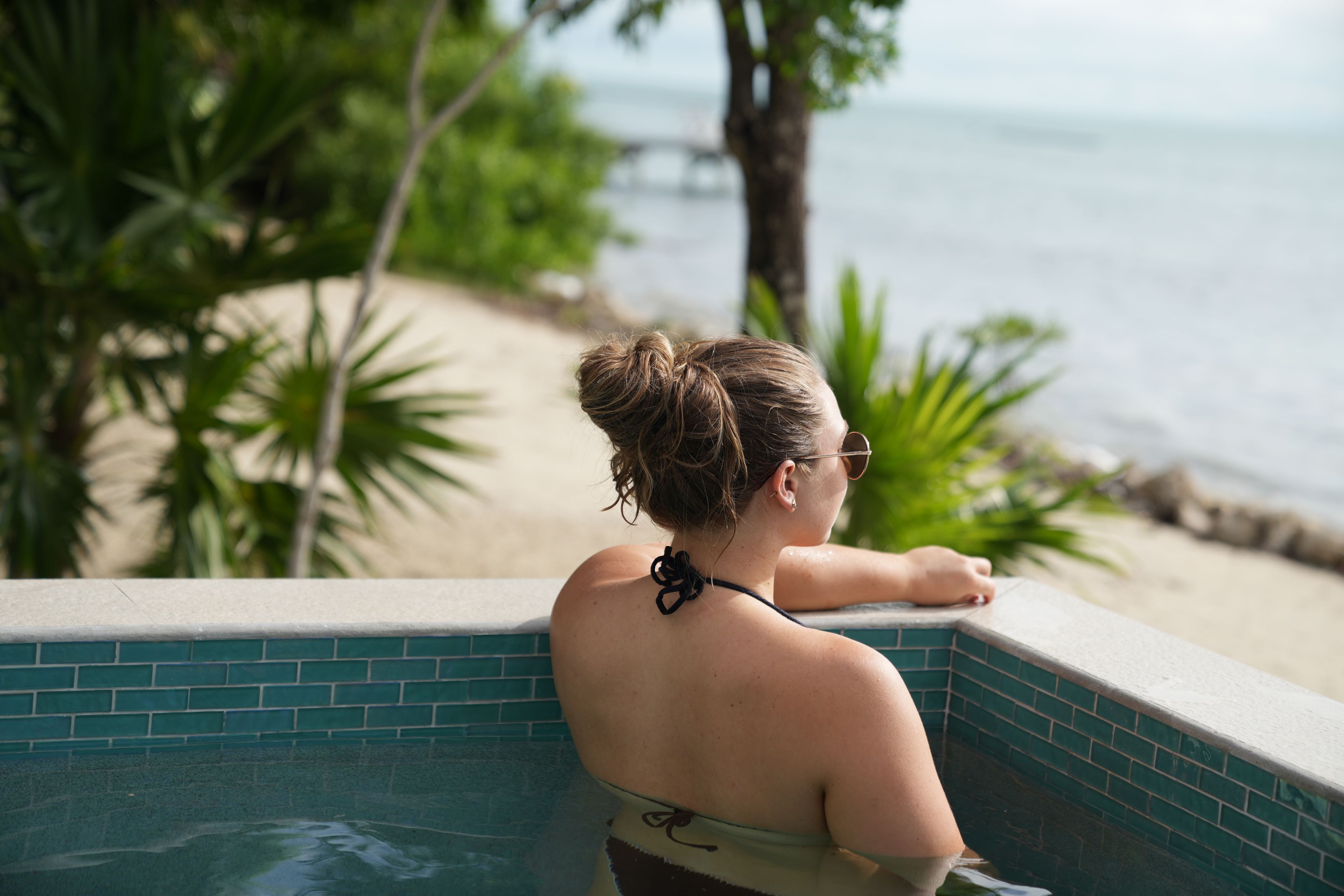A person relaxing by a pool with a view of the beach and ocean.