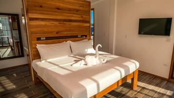 A bedroom with a wooden headboard, a bed with white bedding, a TV mounted on the wall, and a patterned floor.