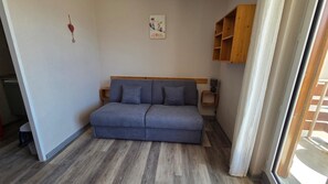 A room with a grey sofa, a wooden cabinet, and a wall-mounted picture. - 1800 Village Studio with a View (Les Deux Alpes)