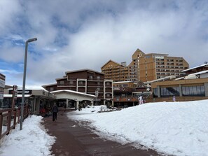 A snow-covered pathway leading to a building with multiple balconies and a ski lift visible in the background. - 1800 Village Studio with a View (Les Deux Alpes)