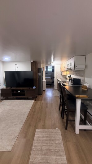 A compact living space with a television, kitchenette, and a dining area.
