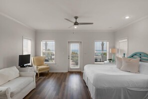A bedroom with a bed, a chair, a television, and a ceiling fan. - Seabreeze 30A (Panama City Beach)