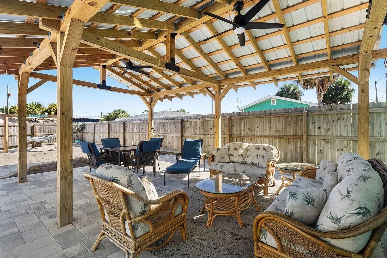 An outdoor patio with wooden furniture and a ceiling fan.