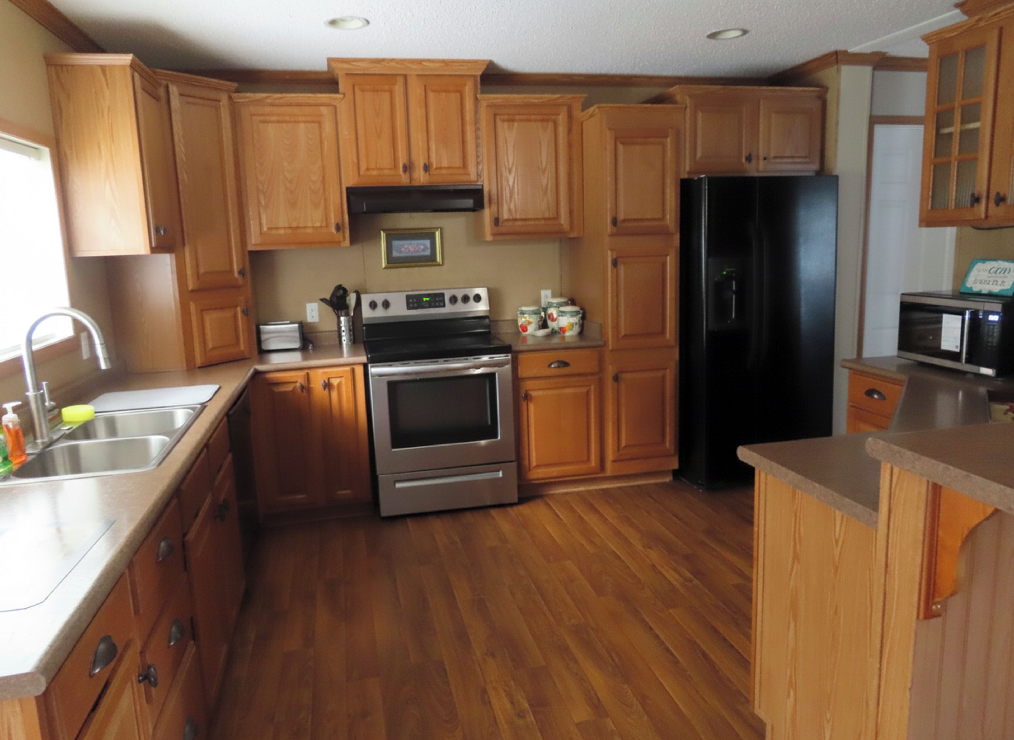 Una cocina con armarios de madera, electrodomésticos de acero inoxidable y un microondas.