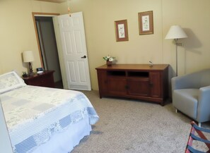 A bedroom with a bed, a dresser, a chair, and a nightstand.