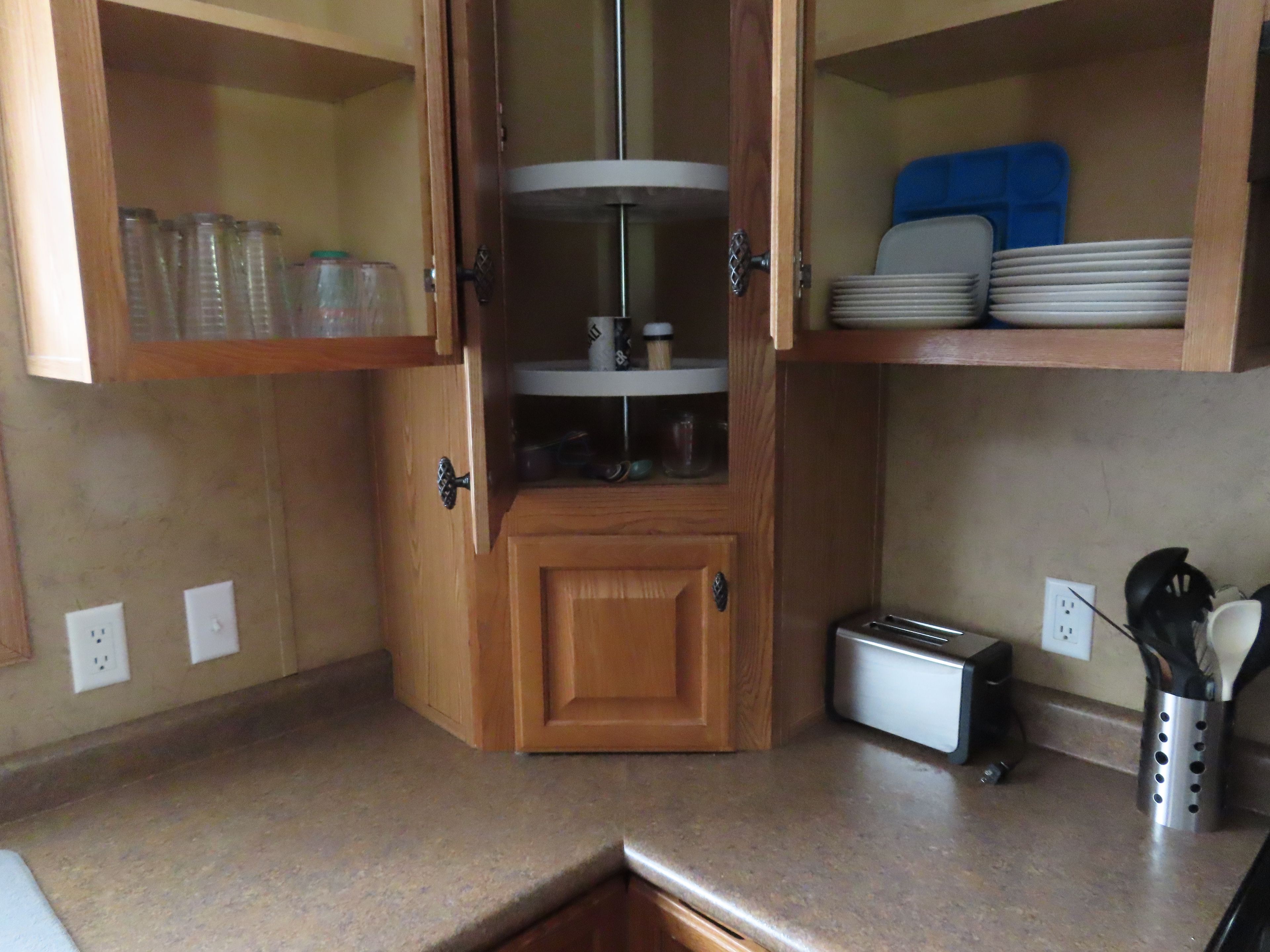 A kitchen with a built-in microwave, a toaster, and a spice rack.