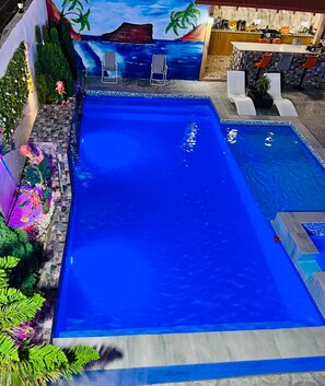 A swimming pool with a tropical mural backdrop, lounge chairs, and a bar area. - Elegant Modern Villa Jayden in Monte Cristi Dominican Republic (Monte Cristi)
