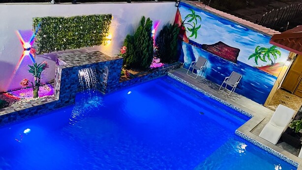 Une piscine dotée d’une terrasse carrelée et d’un petit espace vert.