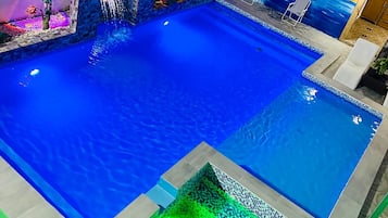 Une piscine dotée d’une terrasse carrelée et d’un petit espace vert.
