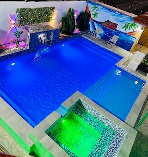 A swimming pool with a tiled deck and a small green area. - Elegant Modern Villa Jayden in Monte Cristi Dominican Republic (Monte Cristi)