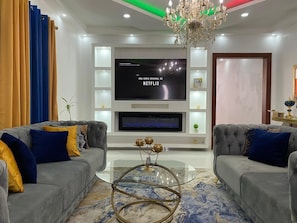 A modern living room with two grey sofas, a glass coffee table, and a flat-screen TV mounted on the wall. - Elegant Modern Villa Jayden in Monte Cristi Dominican Republic (Monte Cristi)