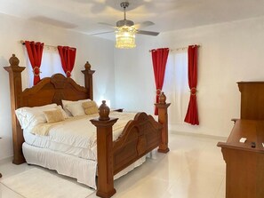 A bedroom with a wooden four-poster bed, a ceiling fan, and red curtains. - Elegant Modern Villa Jayden in Monte Cristi Dominican Republic (Monte Cristi)