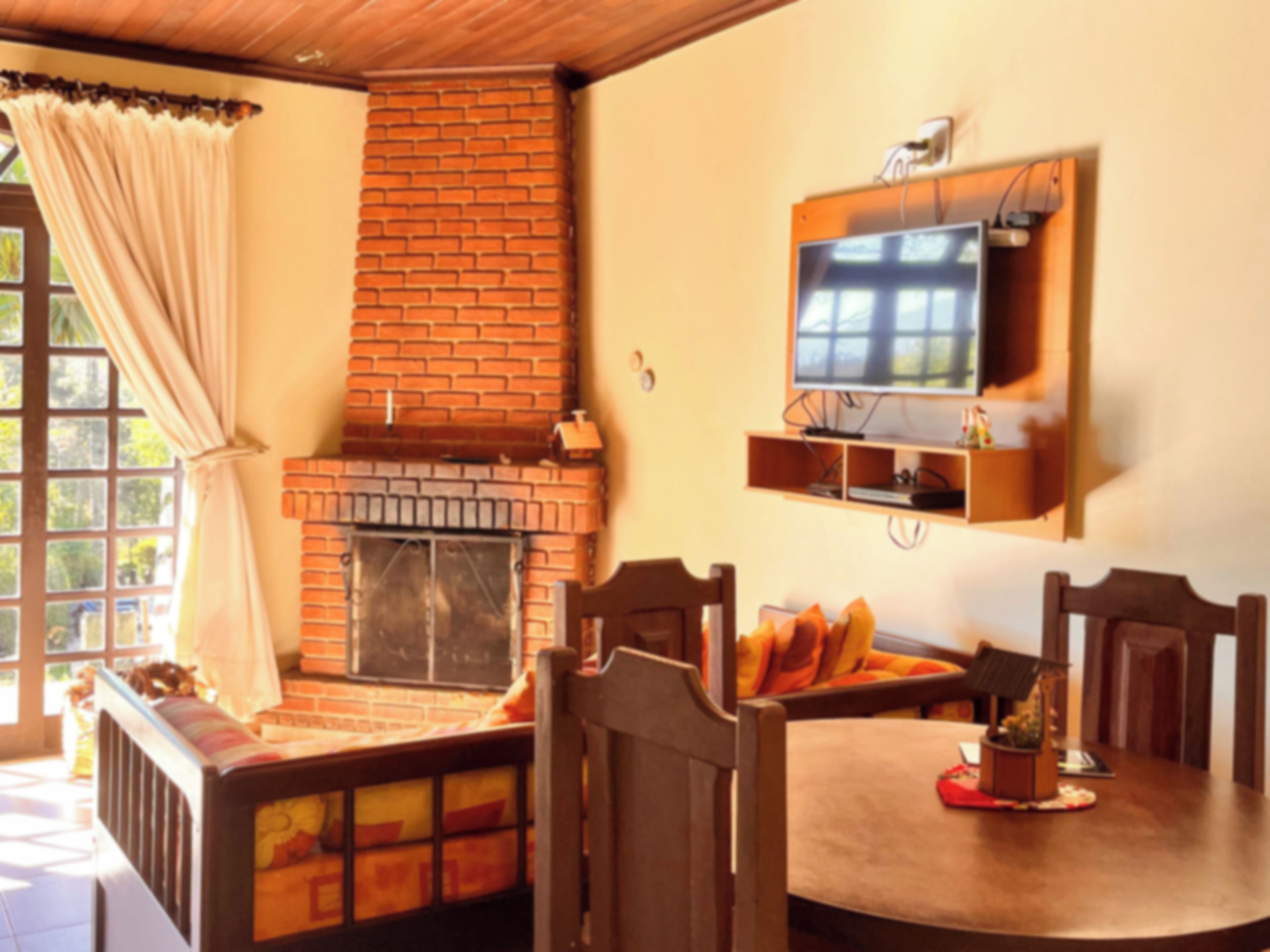 Un comedor con chimenea de ladrillo, sillas de madera y un televisor montado en la pared.