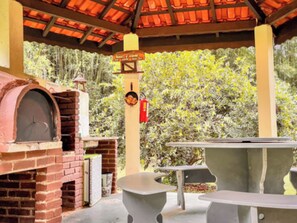 Un patio exterior con horno de ladrillo, una mesa y sillas.