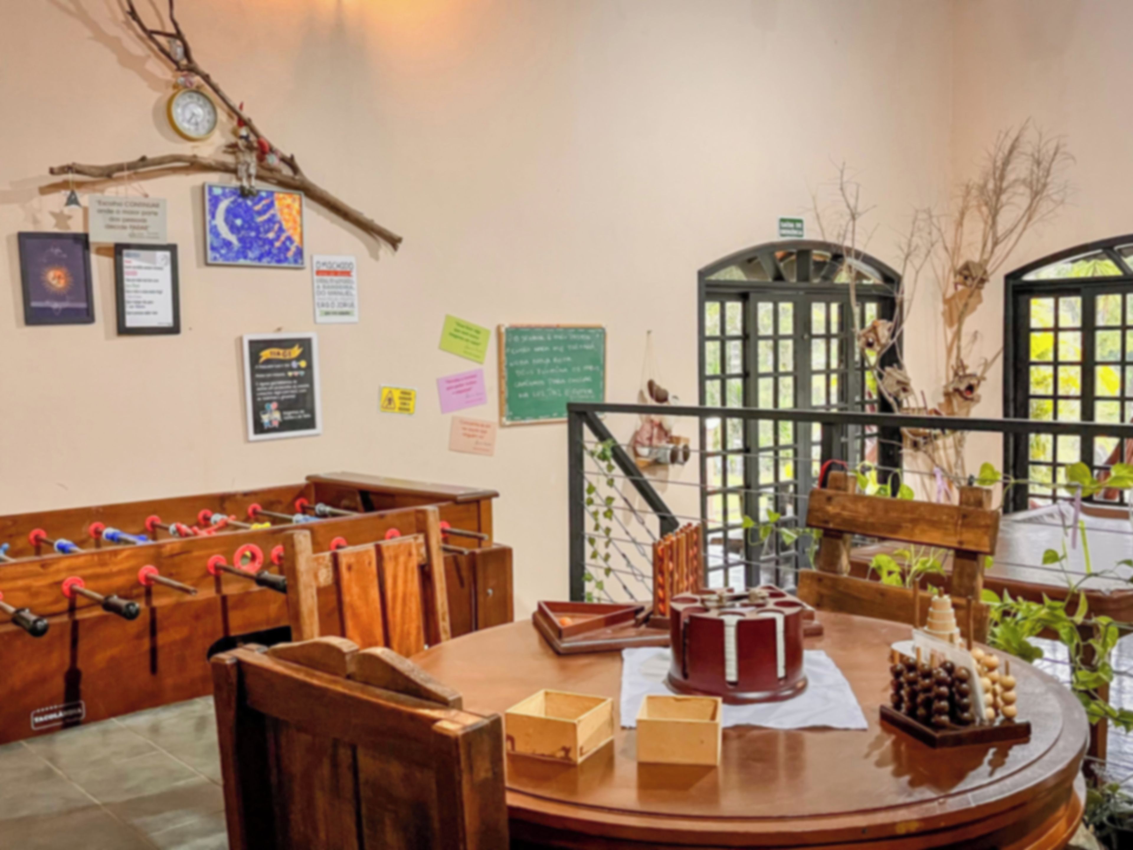 Quarto com mesa de madeira, mesa de pebolim e vários objetos decorativos nas paredes.
