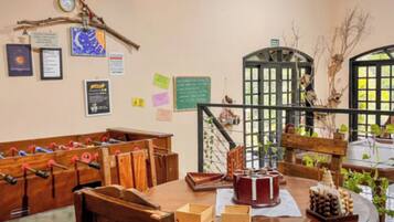 Quarto com mesa de madeira, mesa de pebolim e vários objetos decorativos nas paredes.
