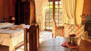 A room with a bed, a wooden chair, a table with a placemat, and a fireplace.