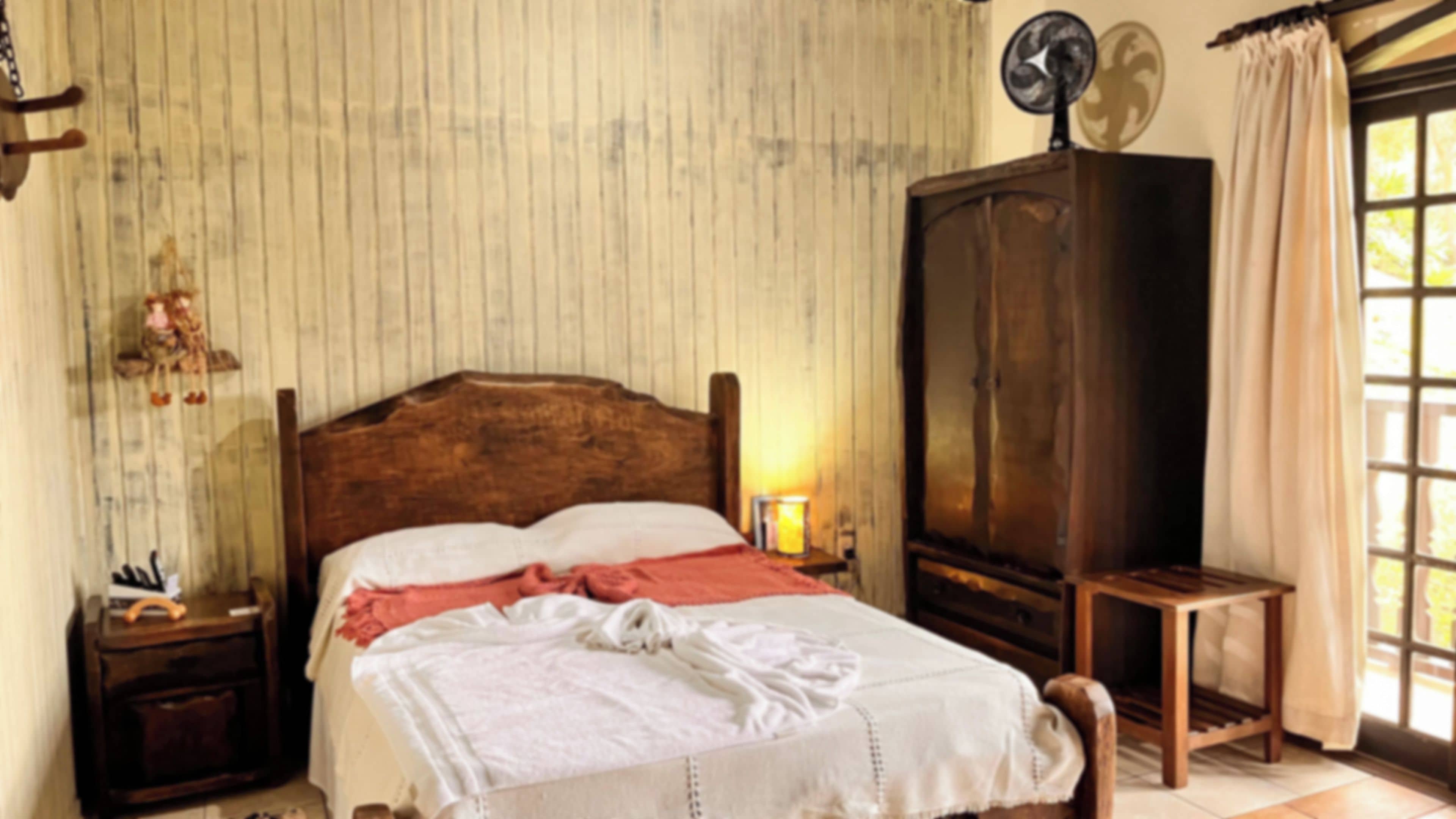 Un dormitorio con una cama de madera, una mesita de noche, un armario y una ventana con cortinas.