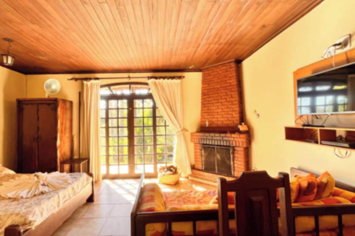 A bedroom with a bed, a fireplace, a television, and a window with curtains.